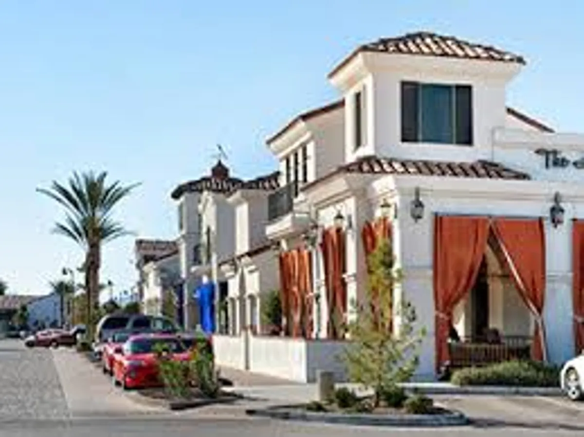 The photo shows the exterior of the building, framed by palm trees and accented with pops of red from parked cars. The scene suggests a lively, well-kept community with inviting walkways and a vibrant atmosphere, reflecting the social and active lifestyle described in the section.