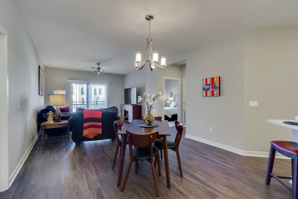 A versatile dining and living area where a sleek table and comfortable sofa provide a space for both meals and relaxation. Striking artwork adds an artistic touch, enhancing the sophisticated atmosphere.